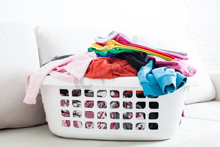 在篮子里洗衣服，在沙发上放一叠干净的亚麻布。五颜六色的干净衣服
