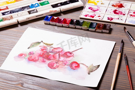 创意涂鸦摄影照片_艺术品，在木桌上用绘画工具画樱桃的水彩画。水彩画《樱桃》
