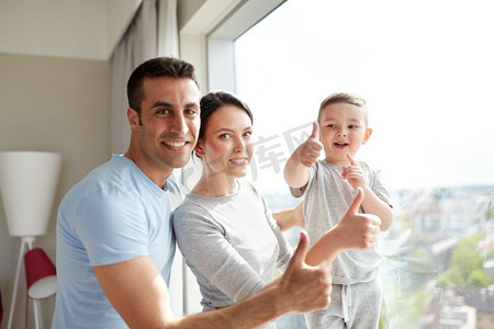 人和家庭的概念-幸福的父母和小儿子在家中的窗户上竖起大拇指。幸福的家庭在窗前