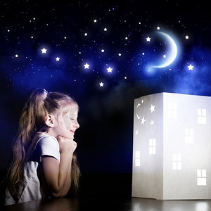 睡觉做梦摄影照片_夜里做梦。可爱的小女孩看着房子的模型做梦