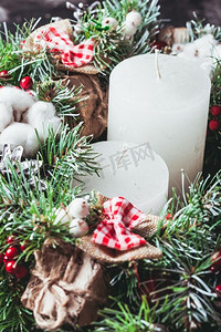 圣诞花环摄影照片_红白相间的圣诞花环蜡烛。红白相间的圣诞花环，上面有蝴蝶结和作为蜡烛的棉花