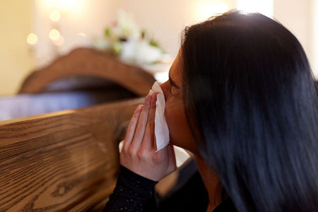 人与哀悼概念--教堂葬礼上哭泣的棺材女人。教堂葬礼上，一名抬着棺材的妇女哭泣