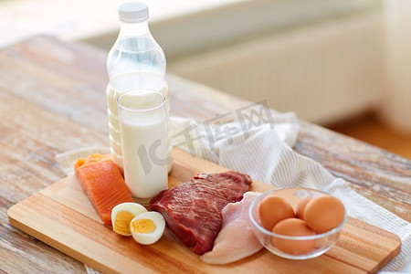 丰富的食物摄影照片_天然食品、健康饮食、蛋白质饮食理念--生肉片、鱼、奶、蛋摆在木桌上。木桌上的天然蛋白质食物