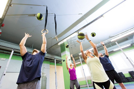 药球摄影照片_健身、运动和锻炼的概念--在健身房进行药球训练的人群。在健身房进行药球训练的一群人