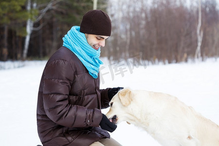 他在散步摄影照片_和他最好的朋友一起。一个男人带着拉布拉多犬在冬季公园散步