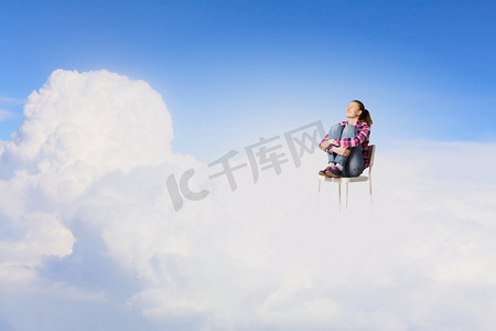 云上的女人摄影照片_天堂里的女人。坐在椅子上的年轻女子坐在高空的云上