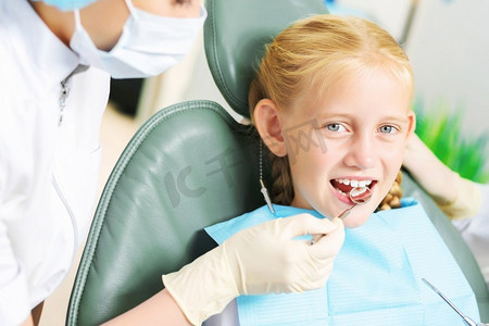 口服摄影照片_牙齿检查可爱的微笑的女孩在牙医坐在扶手椅
