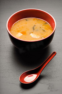 一个特写镜头的勺子和一个汤盘与美味的味噌汤。