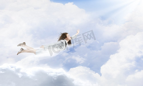 会飞的女超人。年轻漂亮的女商人在蓝天上飞翔