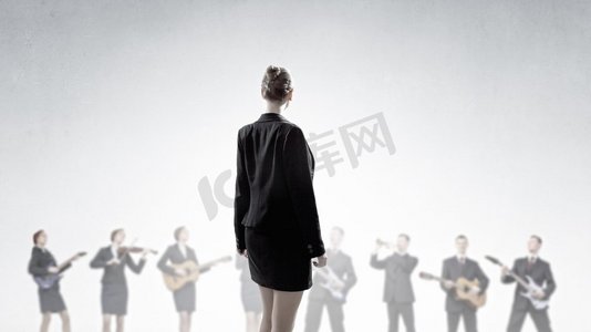 书鼓摄影照片_一人乐队。年轻女子背着背站着，人们演奏着不同的乐器