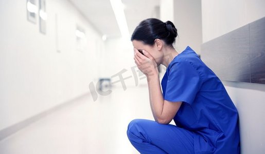 人、药、保健、忧伤--医院走廊里悲伤或哭泣的女护士。医院走廊里悲伤或哭泣的女护士