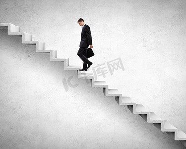 年轻的商人走上楼梯，代表成功的概念。在职业阶梯上往上爬