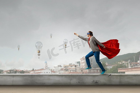女超人摄影照片_她是女超人。年轻果断的女人，穿着红色斗篷，戴着面具