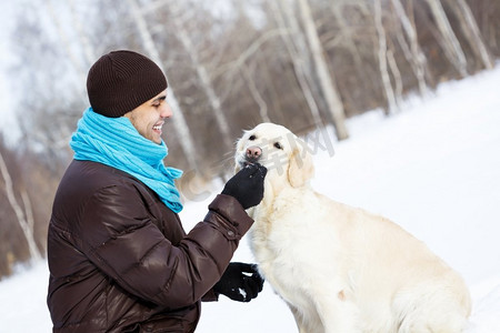 和他最好的朋友一起。一个男人带着拉布拉多犬在冬季公园散步