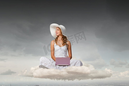 云上的女人摄影照片_女士使用笔记本电脑。坐在云上的年轻女士与膝上型计算机