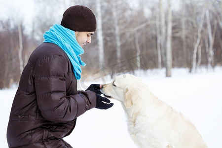 和他最好的朋友一起。一个男人带着拉布拉多犬在冬季公园散步