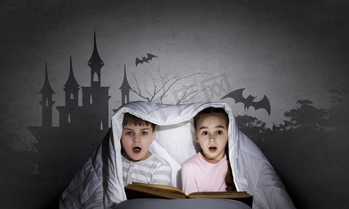 孩子们的噩梦。两个小孩子在毯子下看书