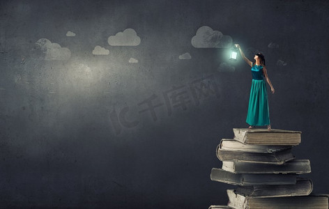 一位身穿绿色连衣裙、提着灯笼的年轻女子站在一堆书上。迷失在黑暗中