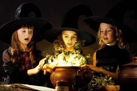万圣节恶魔摄影照片_小女巫。三个万圣节小巫婆在锅上念咒语
