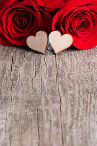 情人节，旧木板背景上的两朵玫瑰和木心