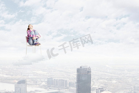 天堂里的女人。坐在椅子上的年轻女子坐在高空的云上
