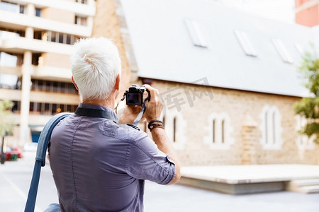 记者节海报摄影照片_在城市里拿着相机的老年男子。寻找好的萌芽