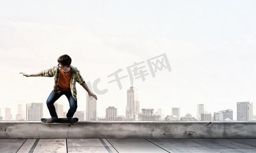 男孩骑滑板。活跃的男人在楼顶上玩滑板