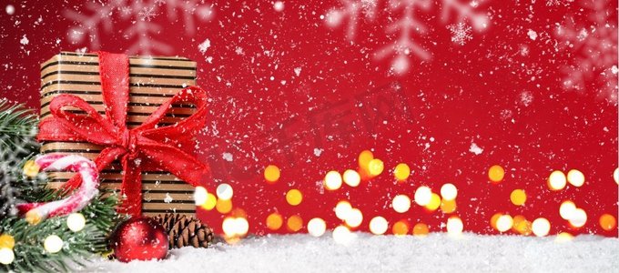 圣诞节装饰摄影照片_圣诞节或新年的节日背景。红色下雪的圣诞节或新年背景上的礼品盒，装饰灯模糊