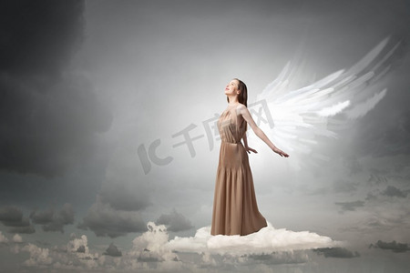 天使爱恋摄影照片_天使女孩飞得很高。天空背景下长着天使翅膀的迷人女子