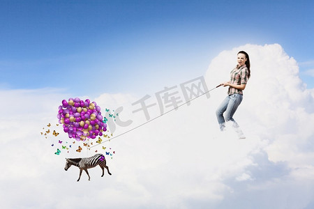 斑马气球摄影照片_斑马上的铅。年轻女子穿着休闲服，斑马在天空中飞翔