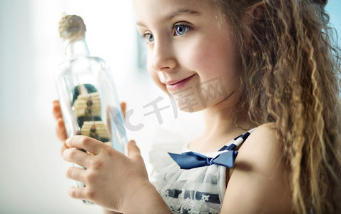 活性摄影照片_一个小孩拿着一个瓶子和一艘船 