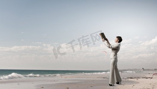 书的海洋摄影照片_拿着书的女人。西装革履，手里拿着旧书的成年女子
