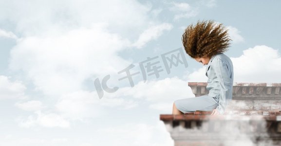 飘动摄影照片_商业上的挑战。一位年轻的女商人坐在楼顶上，一头飘动的头发