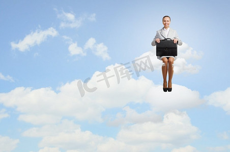 云上的女人。年轻漂亮的女商人坐在城市上空的云端
