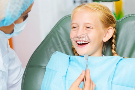 牙齿检查可爱的微笑的女孩在牙医坐在扶手椅