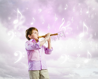 吹长笛的男孩。多云背景下吹长笛的小男孩形象