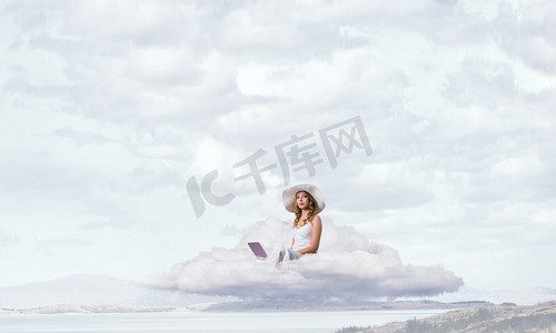 云上的女人摄影照片_女士使用笔记本电脑。坐在云上的年轻女士与膝上型计算机