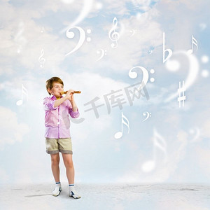 吹长笛的男孩。多云背景下吹长笛的小男孩形象