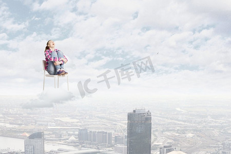 天堂里的女人。坐在椅子上的年轻女子坐在高空的云上