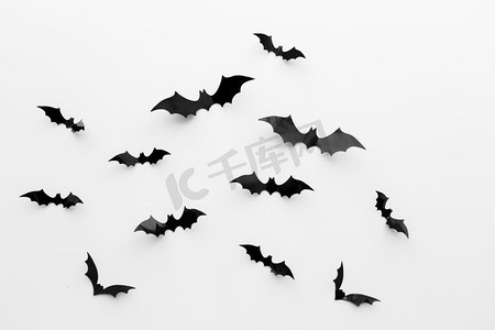 神秘聚会摄影照片_万圣节和装饰概念--黑色纸蝙蝠在白色背景上飞翔。白色背景上的黑纸蝙蝠