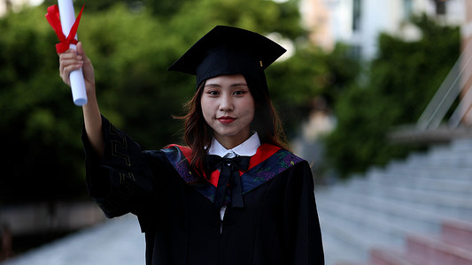 证书荣誉证书摄影照片_手拿毕业证书黑板穿学士服的大学毕业生
