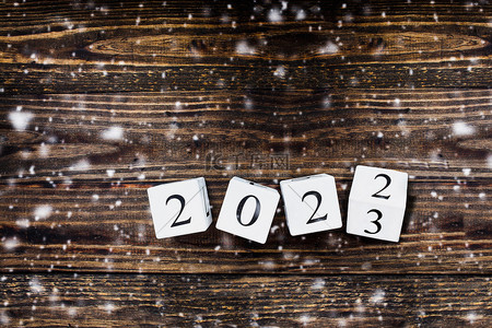 新年new背景图片_木制的白色日历块翻动着2022年至2023年的新年。降雪的桌面视图.