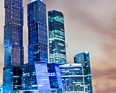 全景和透视图广角查看到钢蓝色背景的玻璃高上升建筑摩天大楼在现代未来派市中心在晚上的业务概念的成功的工业建筑