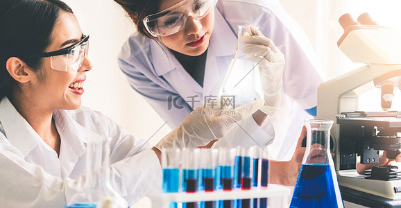 慵懒外套背景图片_一组身穿实验室外套的科学家在实验室工作，同时用试管和科学仪器检查生物化学样品。科学、技术和发展研究概念.