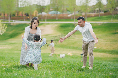 孩子奔向父母在公园的草坪上