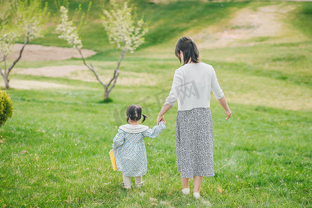 妈妈和孩子摄影照片_妈妈和孩子牵手的背影在草坪上