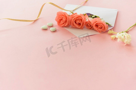 玫瑰创意设计摄影照片_带心形桌子的粉红玫瑰信封