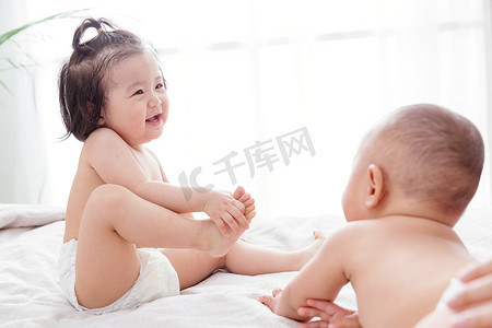 宝宝纸尿裤摄影照片_两个可爱宝宝坐在床上玩耍