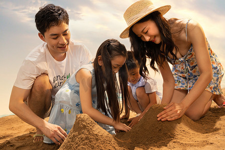 玩沙子摄影照片_快乐的四口之家在沙滩上玩沙子