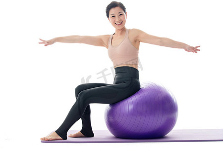 中年女性运动摄影照片_快乐的中年女性坐在瑜伽球上